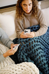 Two friends looking at phones on the couch with blankets #Color_Dusty-Blue