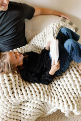 Girl reading book to her dad on the couch with blanket #Color_Cream