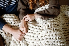 Couple holding hands, Cream Nuzzie blanket on their laps #Color_Cream