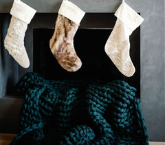 Nuzzie blanket draped in front of fireplace, three neutral stockings on mantle #Color_Forest-Green